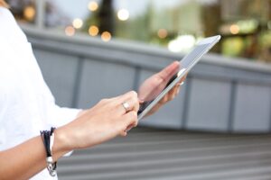 A person holding a tablet computer in their hand, engaged in digital interaction or browsing content.