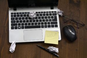 A laptop with a sticky note attached, accompanied by a computer mouse, set on a clean workspace.