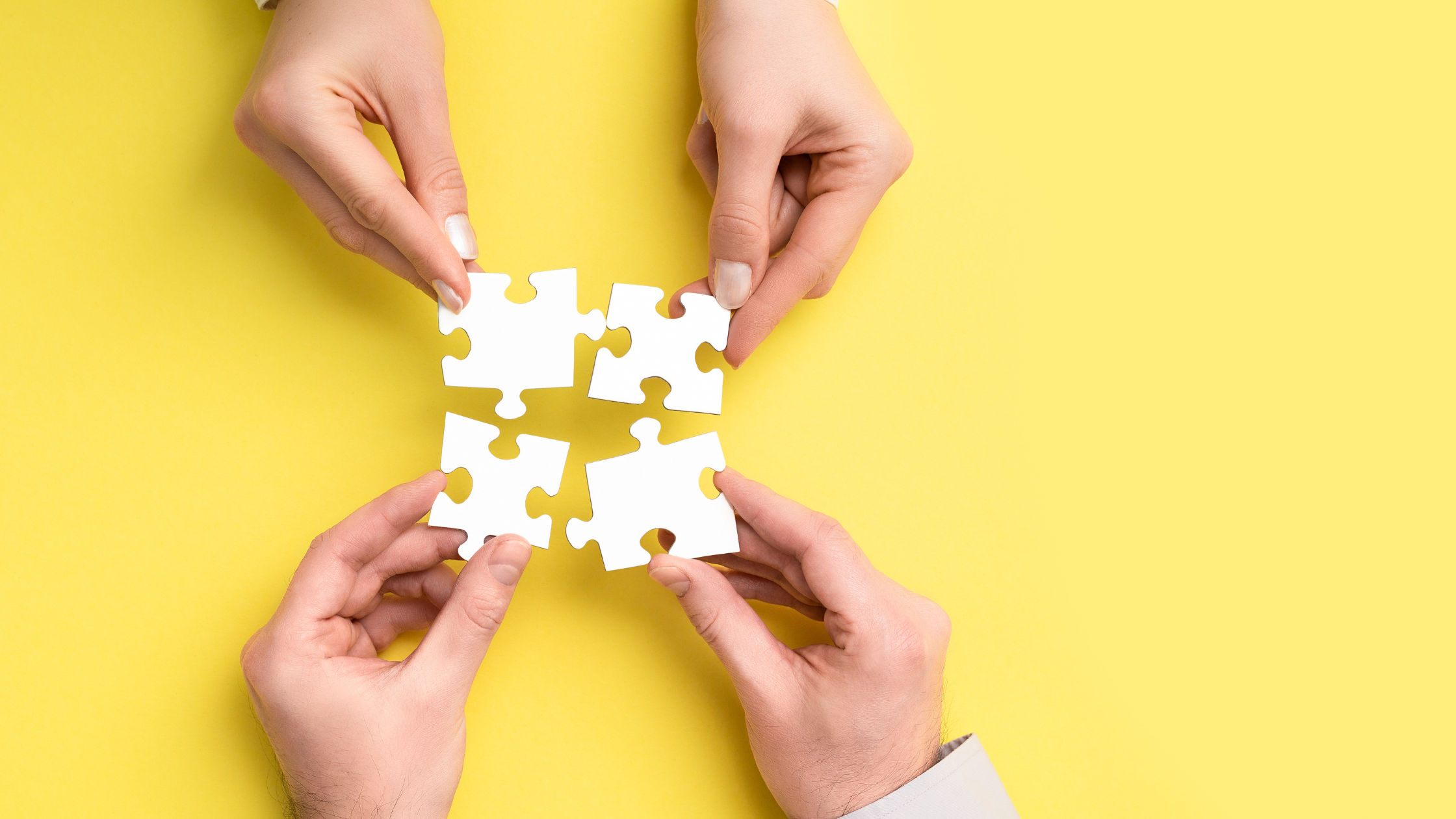 yellow background with four hands holding puzzle pieces